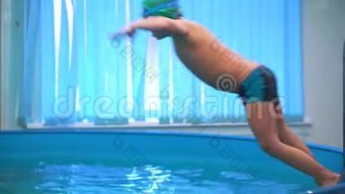 游泳池里的男孩带着泳镜跳进水里。